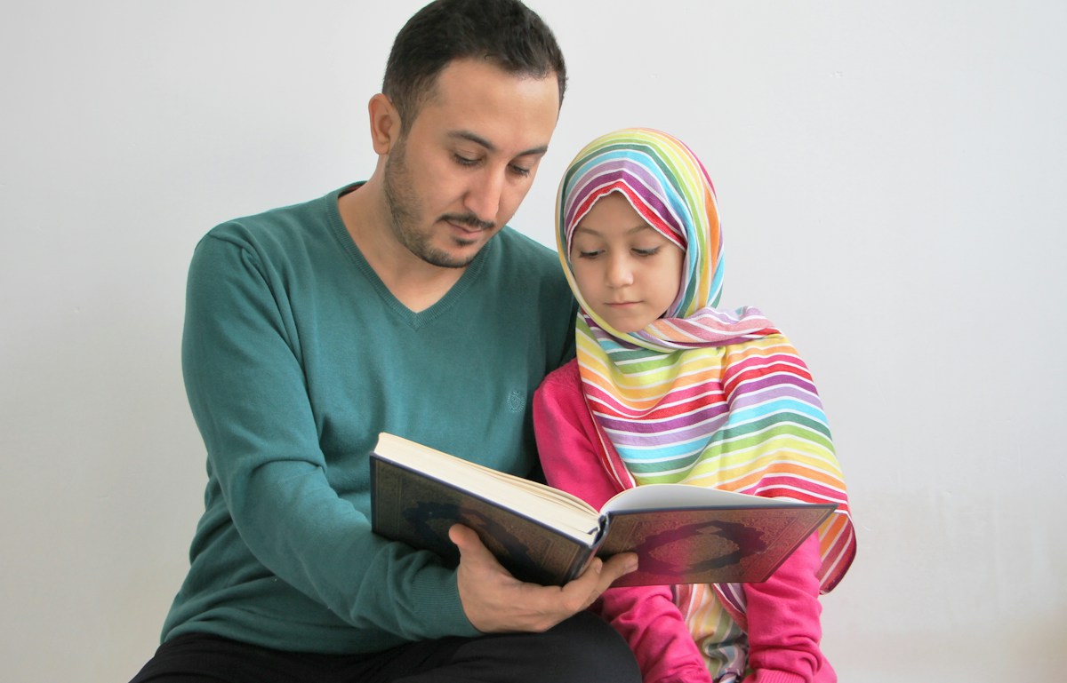 Parent and daughter reading the Quran together